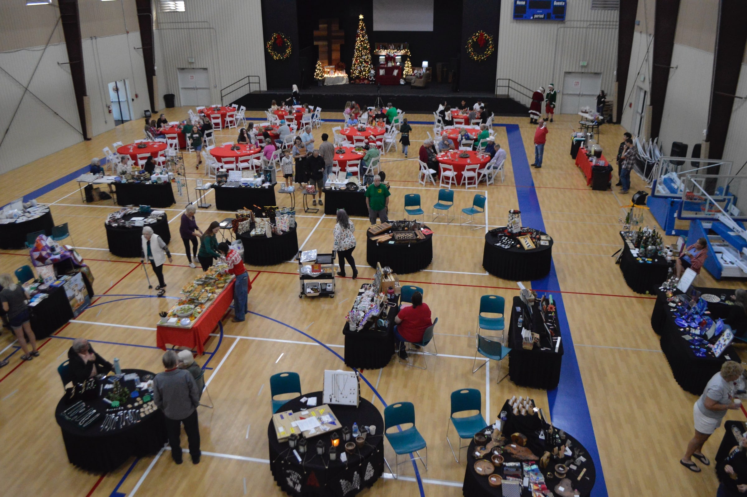 The Paloma gymnasium filled with round tables and booths during a community event, seen from above