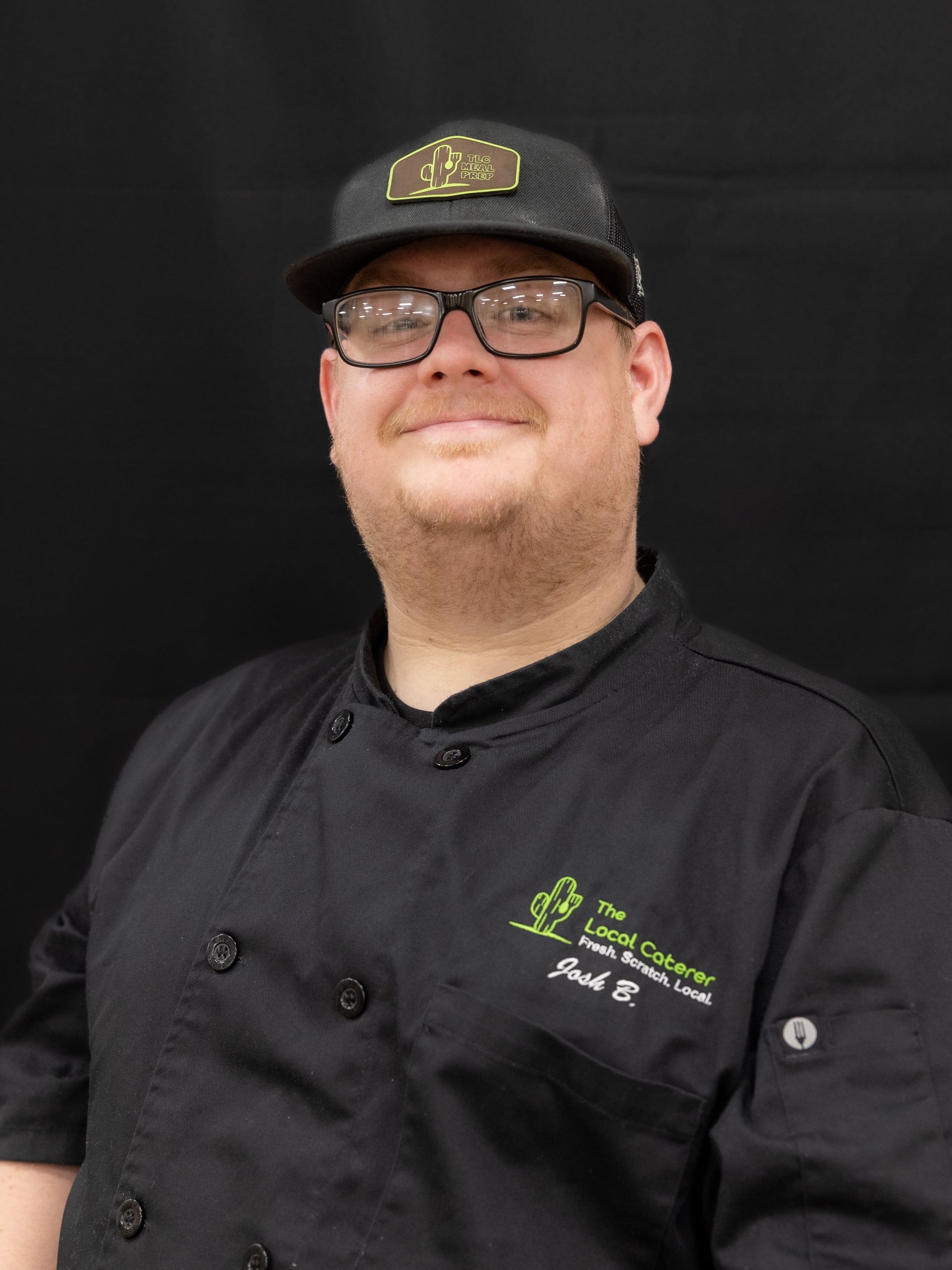 Josh Bakken, Head Chef, in a black chef’s jacket with The Local Caterer logo