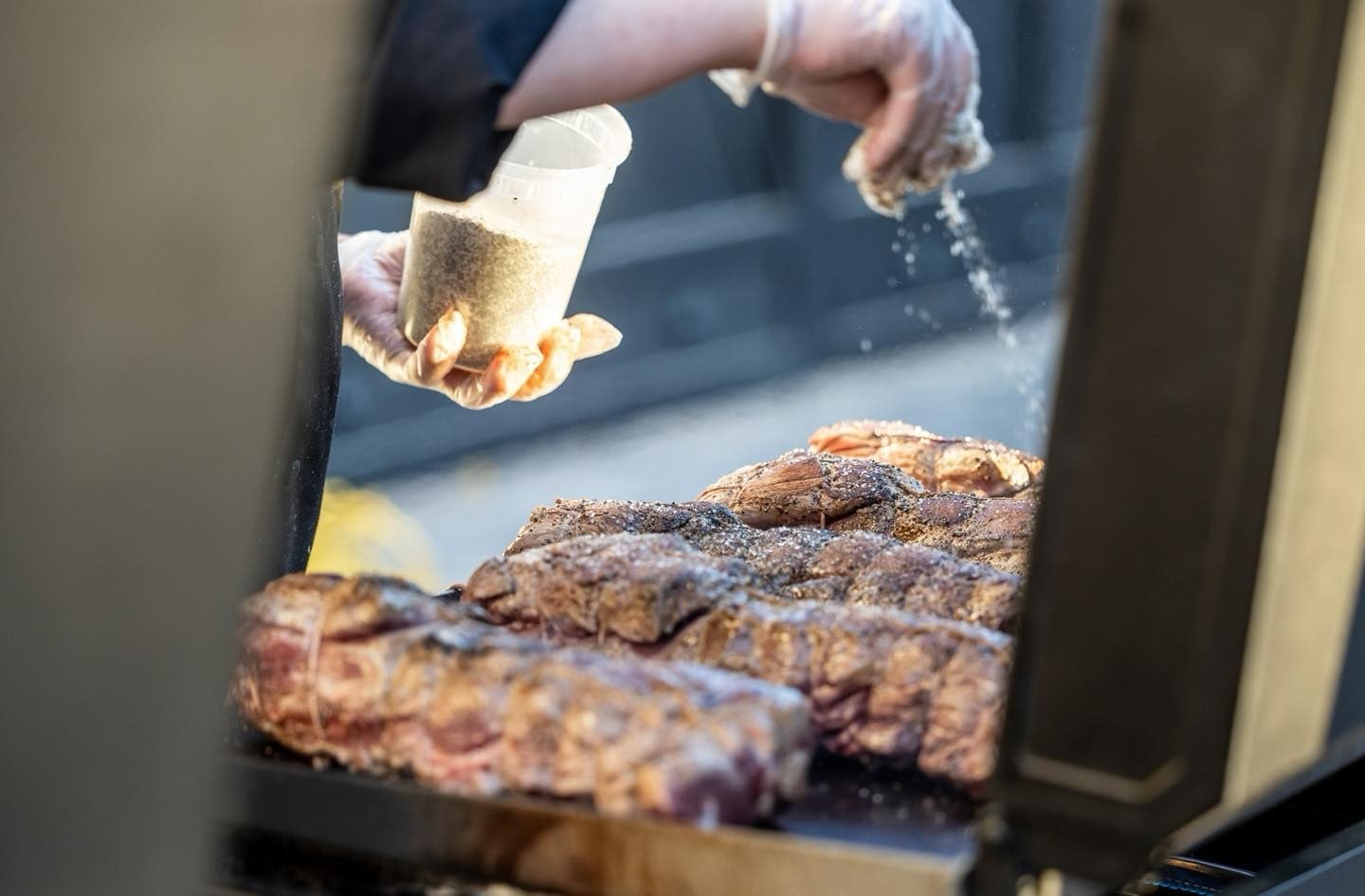 A chef seasons steaks on the grill