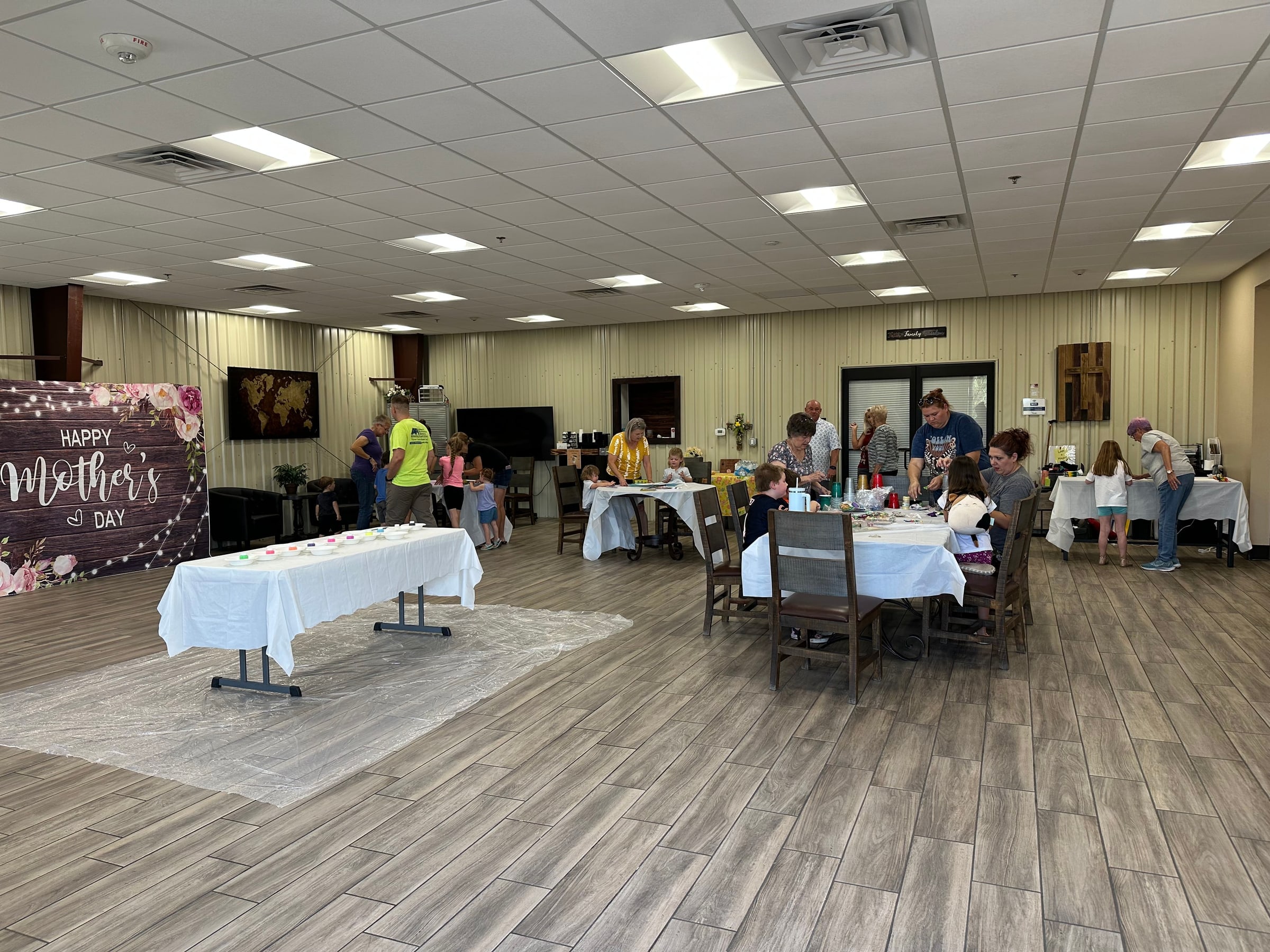 Families gather around decorated tables in the hall for a Mother’s Day Paloma Table meal