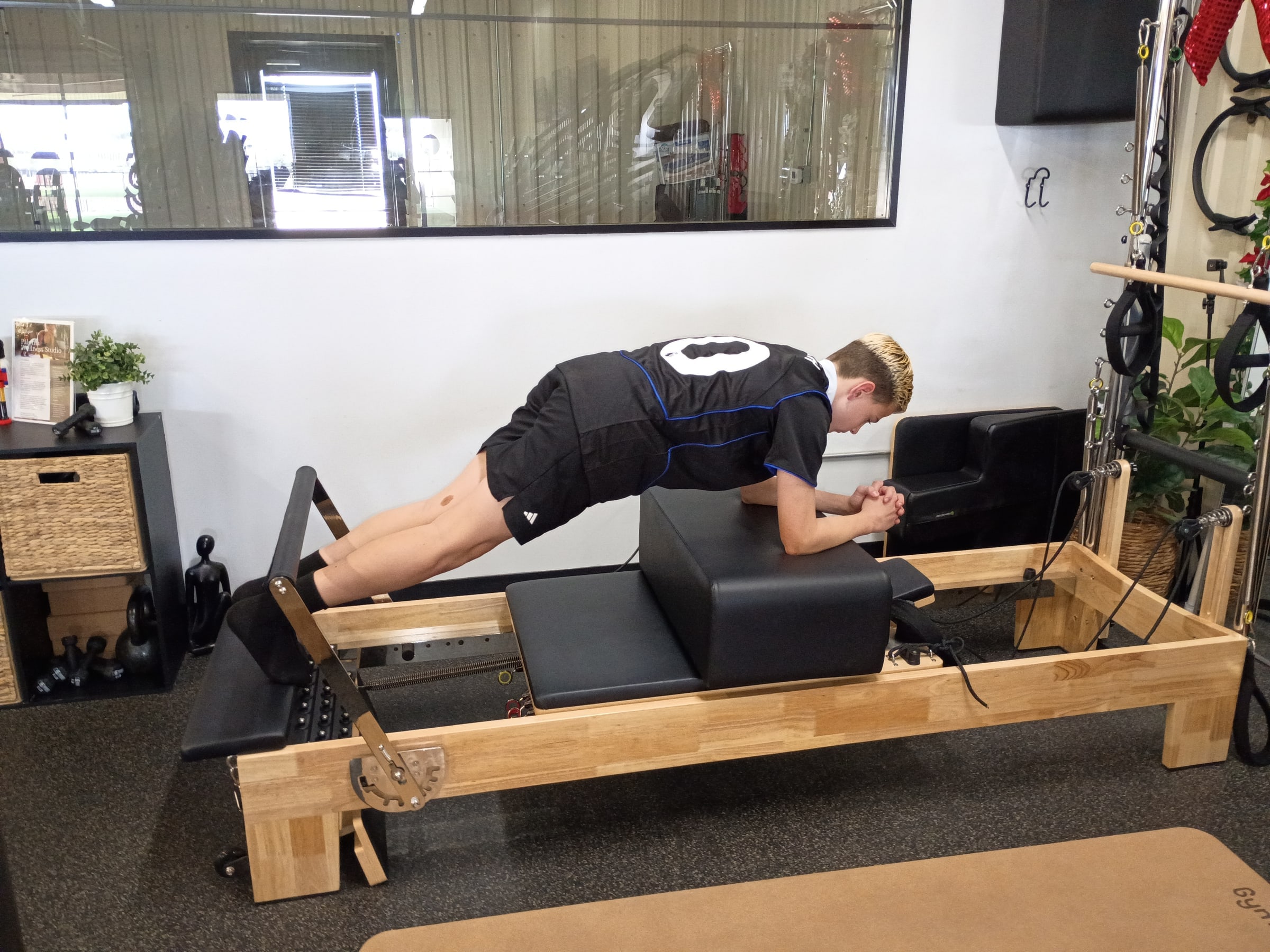 A man holds a plank on a Pilates reformer at Paloma Wellness Studio