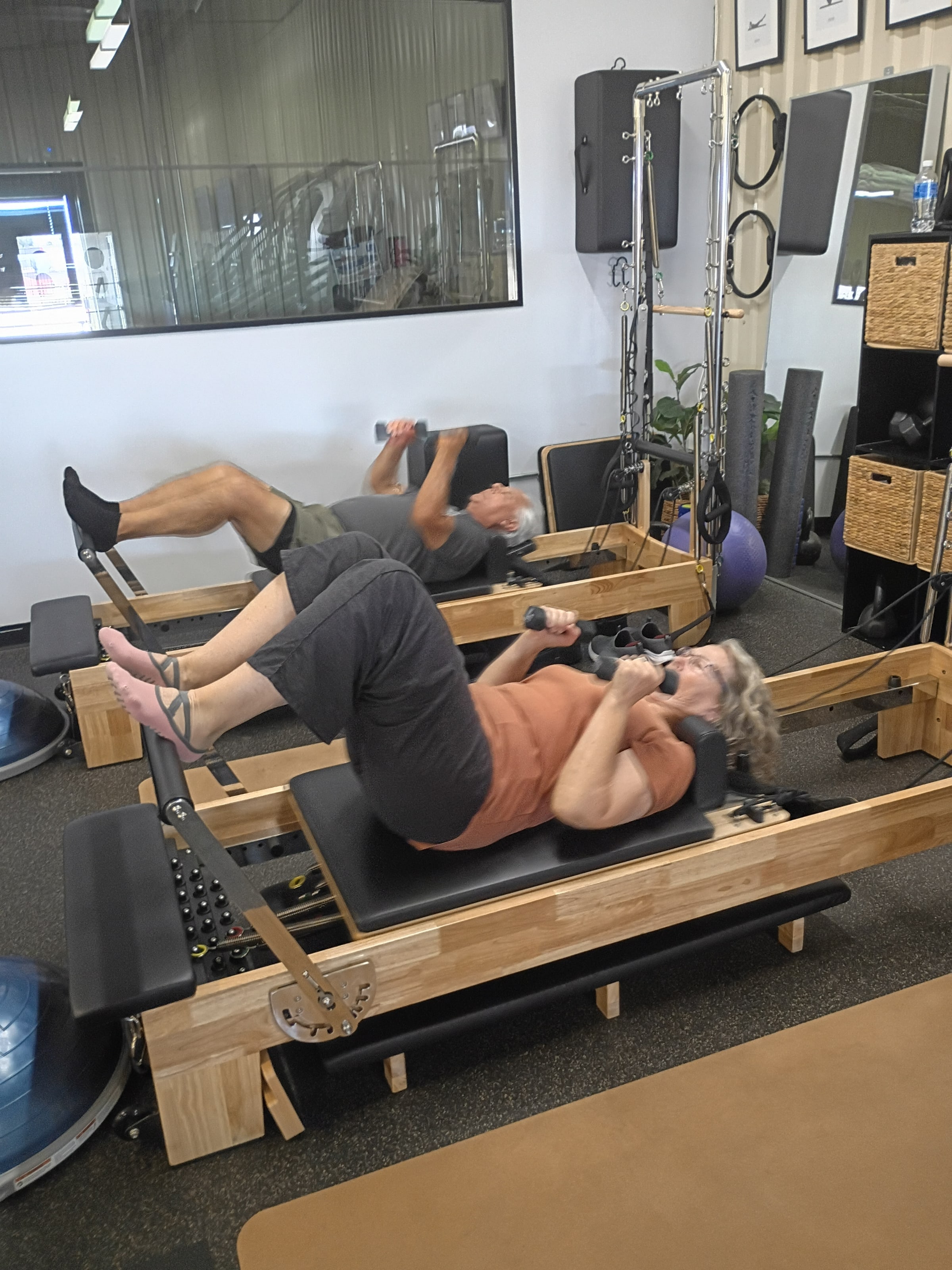 A client exercises on a Pilates reformer with an instructor guiding her at Paloma Wellness Studio